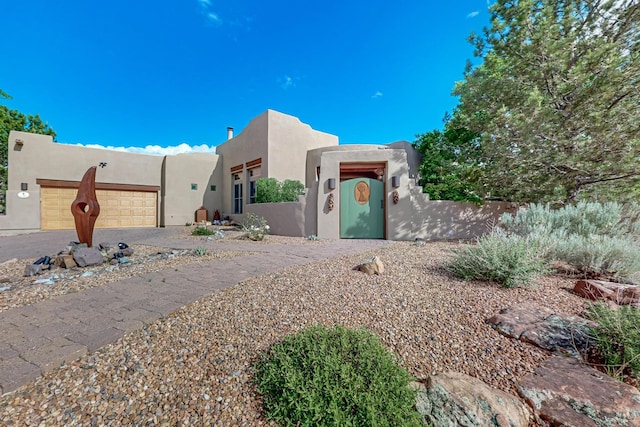 138 E Chili Line, Santa Fe, NM 87508 - pueblo revival-style home with stucco siding, an attached garage, and driveway