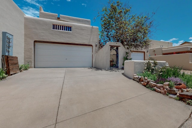 3260 La Paz, Santa Fe, NM 87507 - pueblo-style home with concrete driveway, stucco siding, and a gate