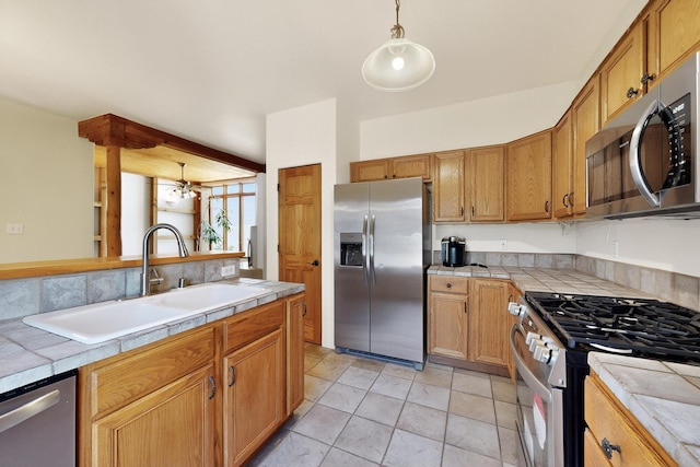 3260 La Paz, Santa Fe, NM 87507 - kitchen featuring appliances with stainless steel finishes, a sink, tile counters, hanging light fixtures, and brown cabinetry