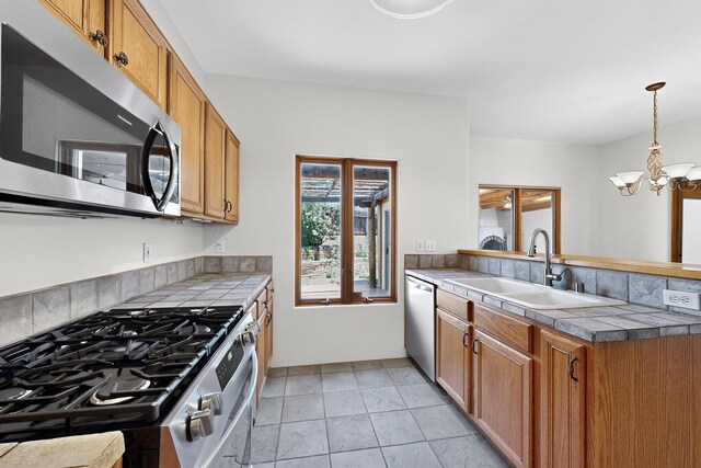 3260 La Paz, Santa Fe, NM 87507 - kitchen featuring appliances with stainless steel finishes, a sink, a peninsula, a chandelier, and brown cabinets