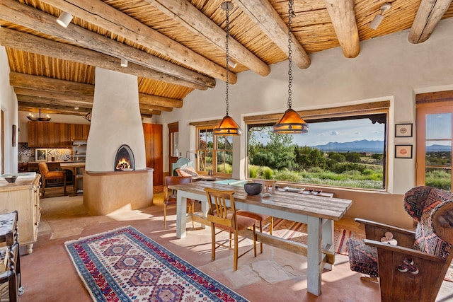 26 Camino Los Angelitos, Santa Fe, NM 87540 - dining space featuring wood ceiling with exposed beams, healthy amount of natural light, concrete flooring, and a large fireplace