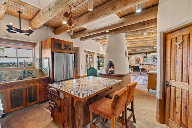 26 Camino Los Angelitos, Santa Fe, NM 87540 - kitchen with freestanding refrigerator, wooden ceiling with exposed beams, a sink, healthy amount of natural light, and tasteful backsplash