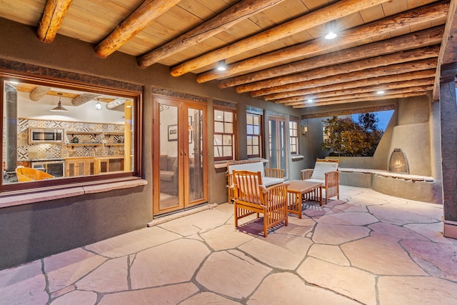 26 Camino Los Angelitos, Santa Fe, NM 87540 - view of patio / terrace featuring a lit fireplace and french doors