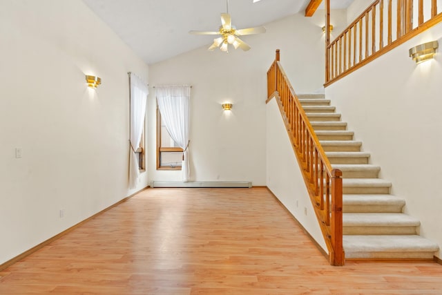 1327 San Ildefonso Rd, Los Alamos, NM 87544 - unfurnished living room with baseboard heating, stairway, wood finished floors, a ceiling fan, and high vaulted ceiling