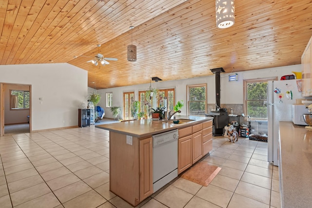 71 Apache Plume Dr, Santa Fe, NM 87508 - kitchen with white appliances, a sink, light tile patterned flooring, a wood stove, and vaulted ceiling
