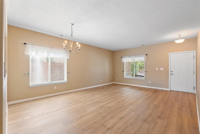 2613 Camino Catalonia, Rio Rancho, NM 87124 - empty room featuring a chandelier, light wood-type flooring, a textured ceiling, and baseboards