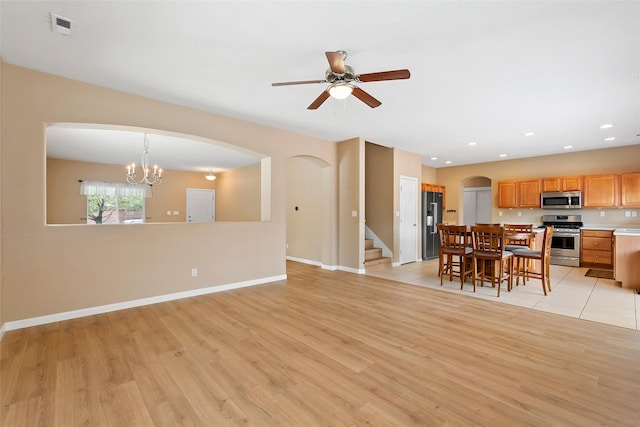 2613 Camino Catalonia, Rio Rancho, NM 87124 - living room with light wood-style flooring, arched walkways, ceiling fan, baseboards, and stairs