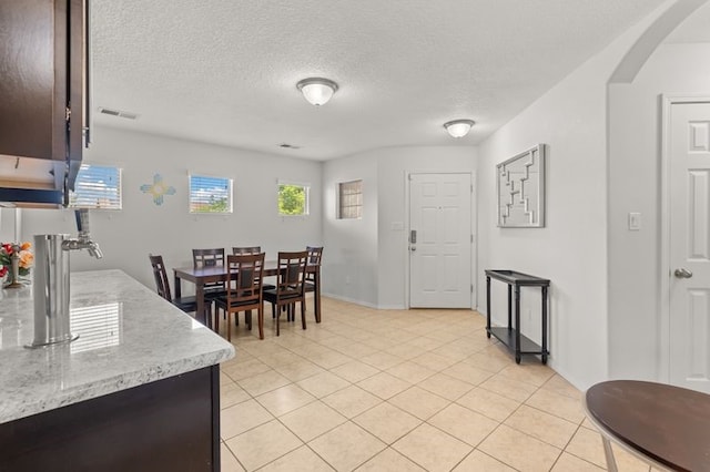 6280 Nardos Rd NW, Albuquerque, NM 87114 - dining room with arched walkways, light tile patterned flooring, and a textured ceiling