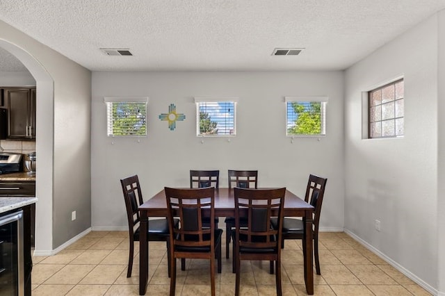 6280 Nardos Rd NW, Albuquerque, NM 87114 - dining room featuring plenty of natural light, light tile patterned floors, arched walkways, and a textured ceiling