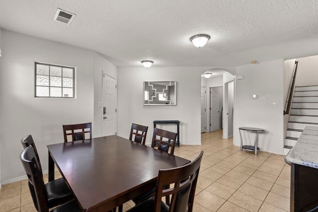 6280 Nardos Rd NW, Albuquerque, NM 87114 - dining space with arched walkways, light tile patterned floors, a textured ceiling, stairway, and baseboards