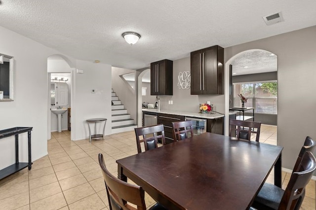 6280 Nardos Rd NW, Albuquerque, NM 87114 - dining room with arched walkways, a textured ceiling, light tile patterned flooring, stairway, and baseboards