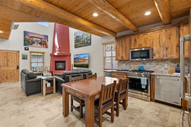 505 Juniper Dr Unit B, Santa Fe, NM 87501 - kitchen with stainless steel appliances, wood ceiling with exposed beams, backsplash, a large fireplace, and brown cabinets