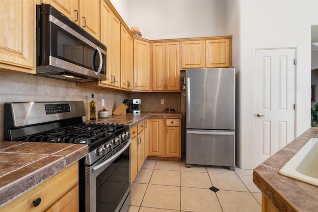 15 Cimarron Pass, Santa Fe, NM 87508 - kitchen with appliances with stainless steel finishes, backsplash, light brown cabinetry, and light tile patterned flooring