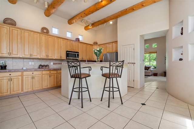 15 Cimarron Pass, Santa Fe, NM 87508 - kitchen with stainless steel appliances, a high ceiling, a breakfast bar area, beamed ceiling, and light tile patterned floors