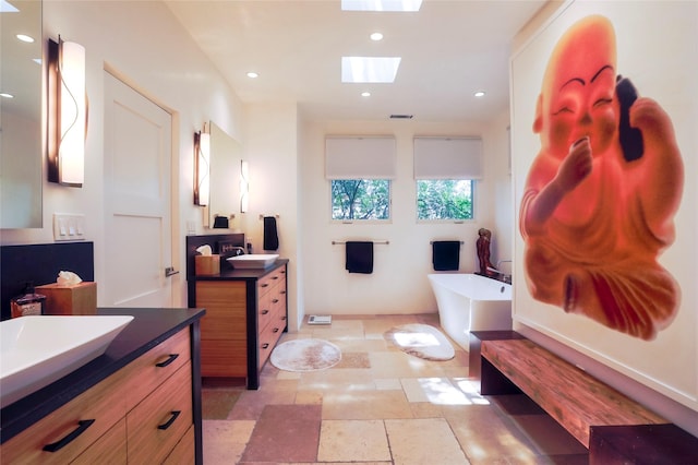 974 Old Santa Fe Trl, Santa Fe, NM 87505 - full bath featuring two vanities, a soaking tub, stone tile floors, recessed lighting, and a skylight