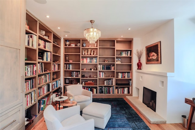 974 Old Santa Fe Trl, Santa Fe, NM 87505 - living area featuring wall of books, a fireplace with raised hearth, a chandelier, wood finished floors, and recessed lighting