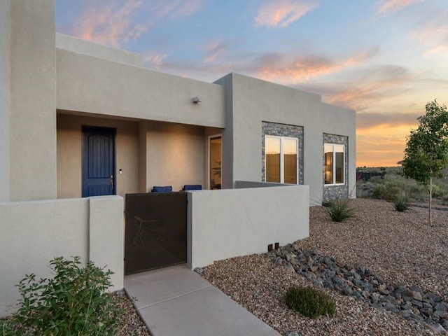 2324 Venada Rd, Rio Rancho, NM 87144 - exterior entry at dusk featuring stucco siding and a gate