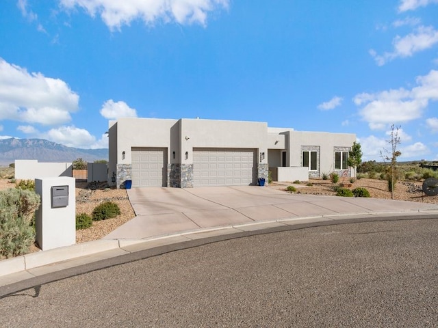 2324 Venada Rd, Rio Rancho, NM 87144 - pueblo-style house with an attached garage, stucco siding, concrete driveway, and a mountain view