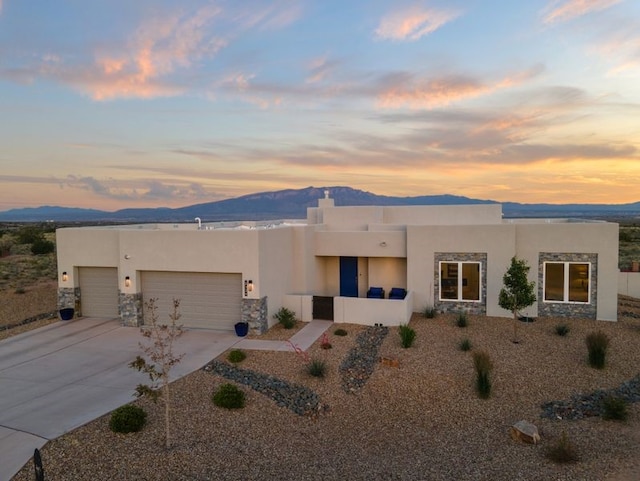 2324 Venada Rd, Rio Rancho, NM 87144 - pueblo-style house featuring stucco siding, stone siding, a garage, and a mountain view