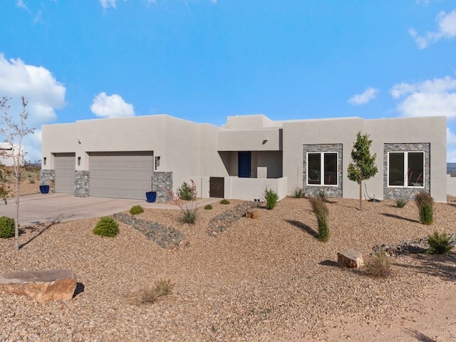2324 Venada Rd, Rio Rancho, NM 87144 - pueblo-style home featuring a garage, stucco siding, driveway, and stone siding