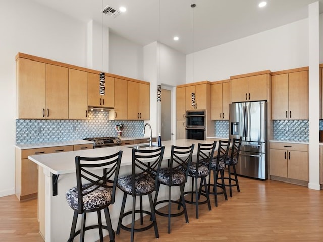 2324 Venada Rd, Rio Rancho, NM 87144 - kitchen featuring stainless steel appliances, light wood-type flooring, light countertops, a towering ceiling, and a kitchen bar