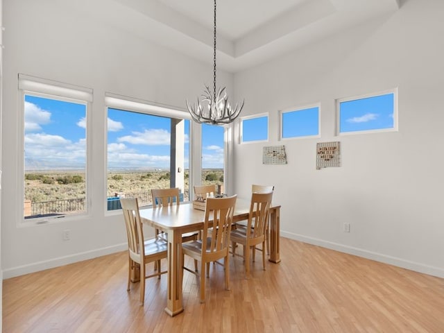 2324 Venada Rd, Rio Rancho, NM 87144 - dining area with a chandelier, light wood-style floors, a towering ceiling, and a raised ceiling
