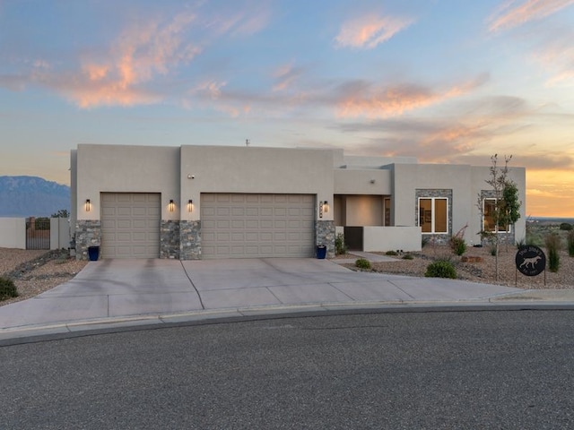 2324 Venada Rd, Rio Rancho, NM 87144 - pueblo-style home featuring a garage, stucco siding, driveway, and stone siding