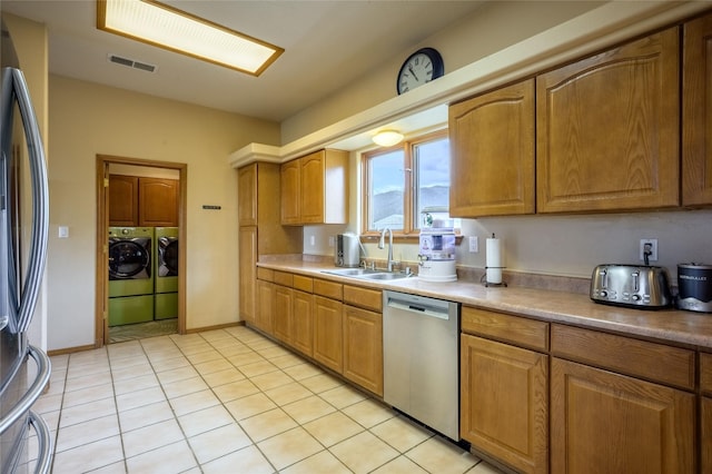 131 Quintana Rd, Questa, NM 87556 - kitchen featuring stainless steel appliances, separate washer and dryer, brown cabinetry, and light tile patterned floors