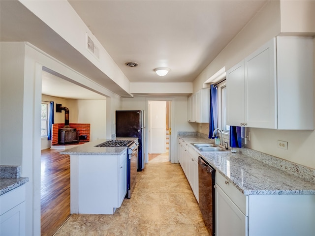 2148 33rd St Unit B, Los Alamos, NM 87544 - kitchen featuring black dishwasher, range with gas cooktop, white cabinetry, a wood stove, and light stone counters