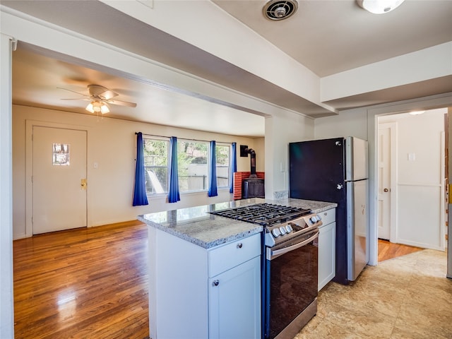 2148 33rd St Unit B, Los Alamos, NM 87544 - kitchen with appliances with stainless steel finishes, a wood stove, a ceiling fan, light stone countertops, and light wood finished floors