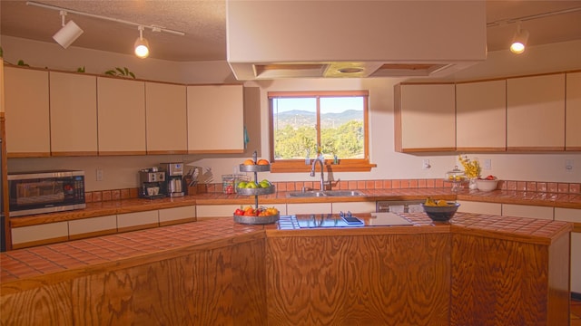 7 Paseo De Rincon, Santa Fe, NM 87508 - kitchen with rail lighting, stainless steel microwave, tile counters, and a textured ceiling