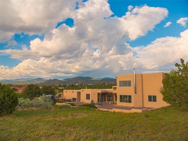 7 Paseo De Rincon, Santa Fe, NM 87508 - rear view of house with a patio area, a mountain view, stucco siding, and a lawn