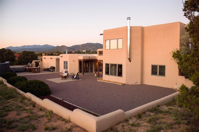7 Paseo De Rincon, Santa Fe, NM 87508 - back of property at dusk featuring a patio, a mountain view, and stucco siding