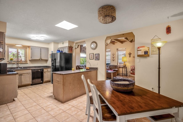 1361 Acequia Borrada, Santa Fe, NM 87507 - kitchen featuring black appliances, dark countertops, light tile patterned floors, a peninsula, and a textured ceiling