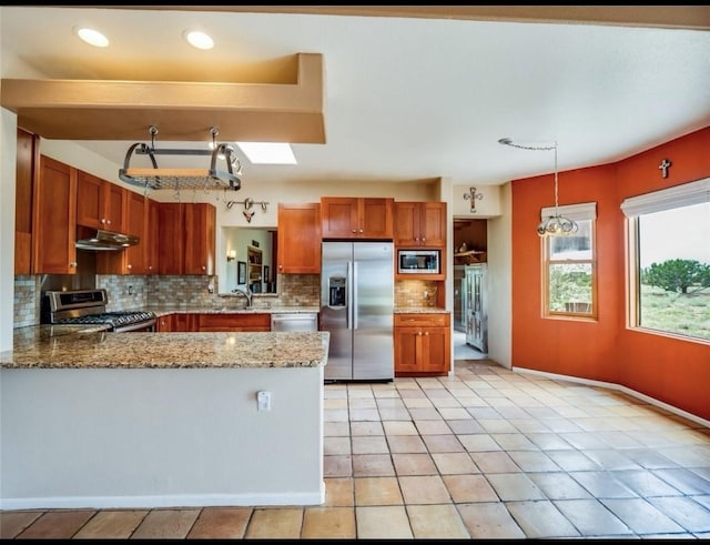 14 Dulce Rd, Santa Fe, NM 87508 - kitchen featuring stainless steel appliances, under cabinet range hood, decorative backsplash, brown cabinets, and a peninsula