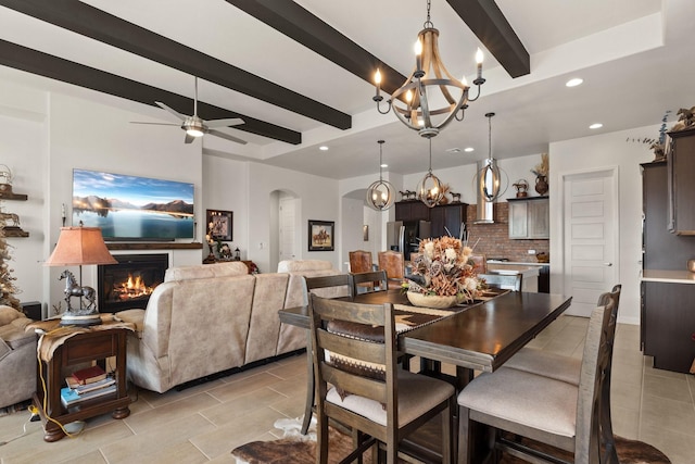 6816 Cleary Loop NE, Rio Rancho, NM 87144 - dining area featuring a chandelier, arched walkways, light tile patterned floors, beam ceiling, and a lit fireplace