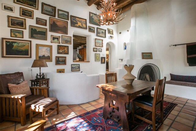 576 Camino Del Monte Sol, Santa Fe, NM 87505 - dining area with light tile patterned floors, a chandelier, arched walkways, beam ceiling, and a high ceiling