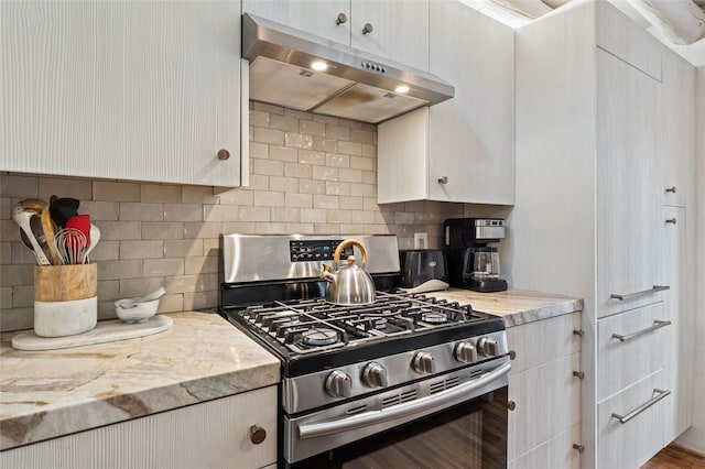 507 Acequia Madre, Santa Fe, NM 87505 - kitchen featuring stainless steel range with gas cooktop, under cabinet range hood, tasteful backsplash, and white cabinets