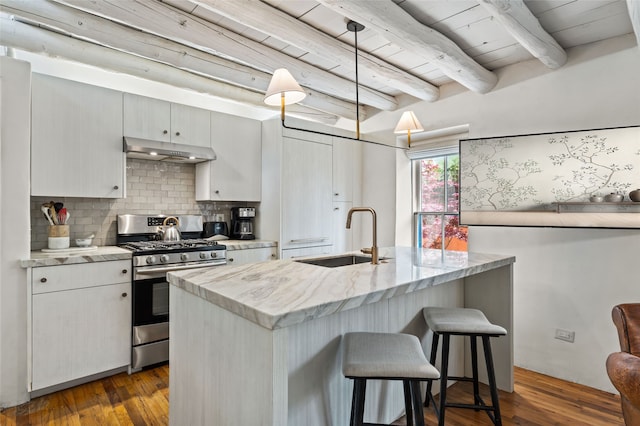 507 Acequia Madre, Santa Fe, NM 87505 - kitchen featuring stainless steel range with gas stovetop, under cabinet range hood, a wood ceiling with exposed beams, decorative backsplash, and a kitchen bar