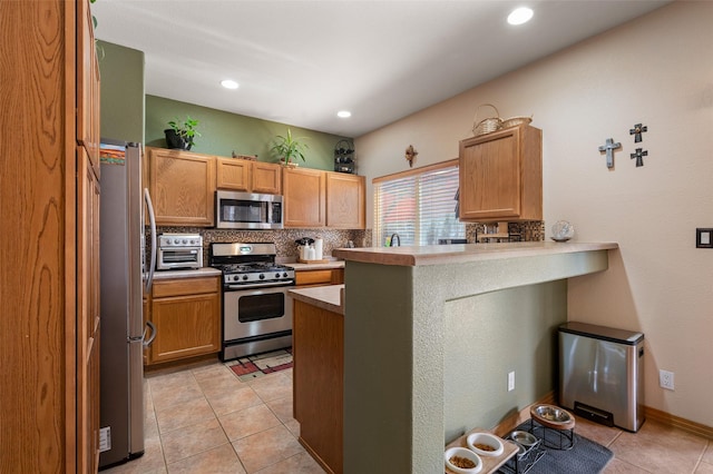 4737 Sundial Way, Santa Fe, NM 87507 - kitchen with appliances with stainless steel finishes, a peninsula, tasteful backsplash, light tile patterned floors, and recessed lighting