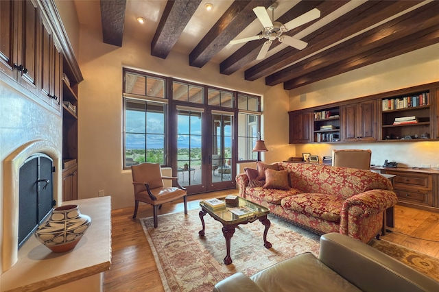 11 E Golden Eagle Rd, Santa Fe, NM 87506 - living area with beamed ceiling, french doors, light wood-type flooring, a ceiling fan, and a fireplace with raised hearth
