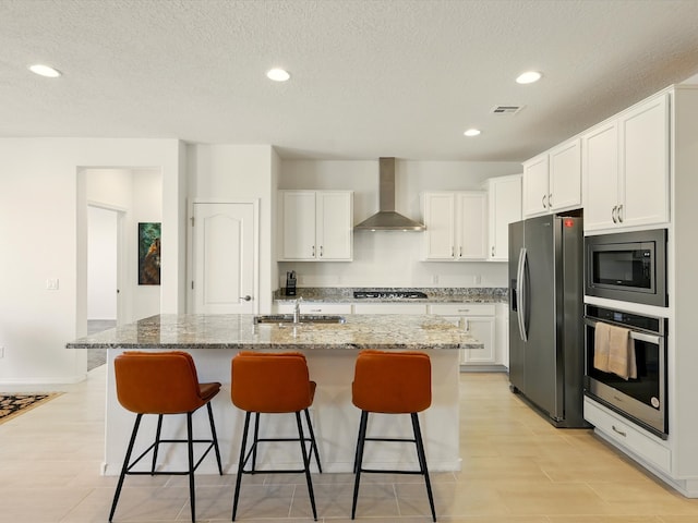 13 Firecrown Ln, Santa Fe, NM 87508 - kitchen with appliances with stainless steel finishes, wall chimney range hood, a kitchen bar, white cabinets, and a textured ceiling