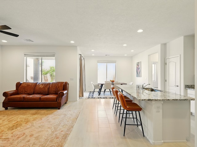 13 Firecrown Ln, Santa Fe, NM 87508 - kitchen featuring plenty of natural light, a kitchen bar, light stone countertops, recessed lighting, and a kitchen island with sink