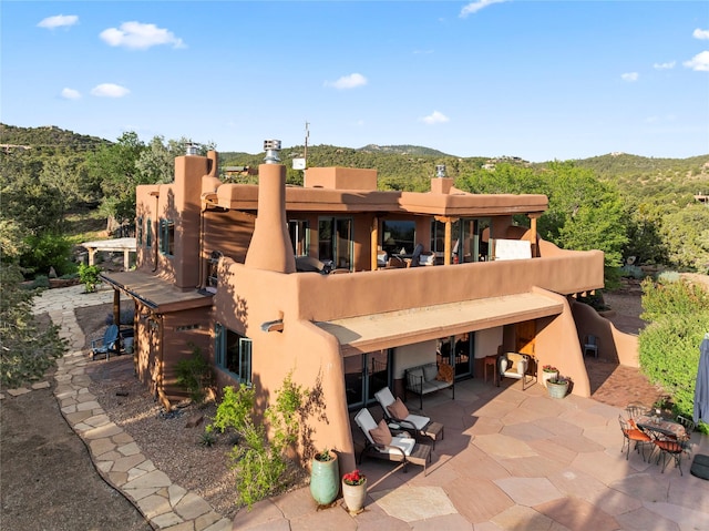 15 Cielo Cumbre Rd, Santa Fe, NM 87505 - back of house featuring stucco siding, a patio, a chimney, and a view of trees