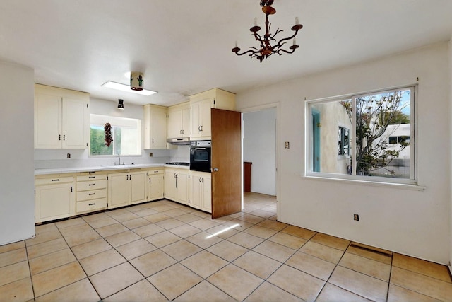 1017 Practilliano Dr, Santa Fe, NM 87505 - kitchen with black oven, light countertops, light tile patterned flooring, a chandelier, and cooktop