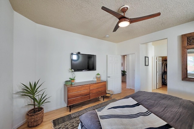 139 Rancho Viejo Blvd, Santa Fe, NM 87508 - bedroom featuring light wood finished floors, a textured ceiling, a spacious closet, ceiling fan, and a closet
