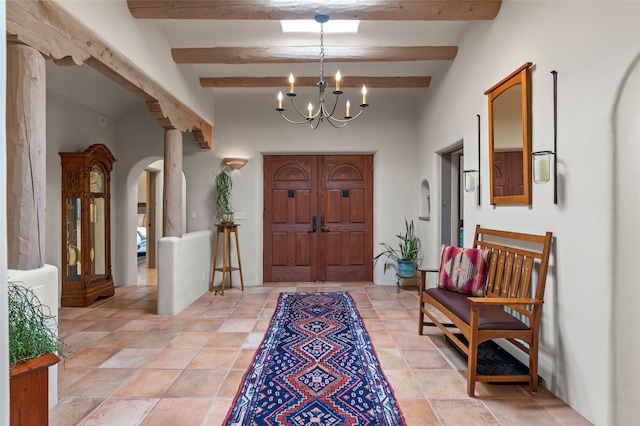 1203 Sierra Del Este, Santa Fe, NM 87501 - entryway featuring arched walkways, a chandelier, beamed ceiling, and stone tile floors