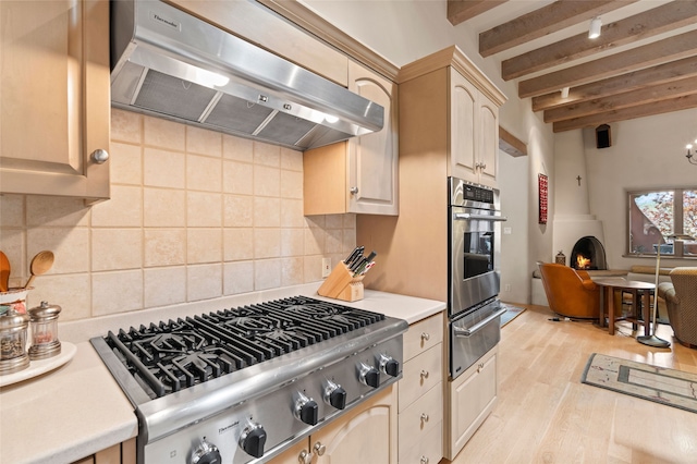 1203 Sierra Del Este, Santa Fe, NM 87501 - kitchen featuring range hood, appliances with stainless steel finishes, a warming drawer, beam ceiling, and light wood-style floors