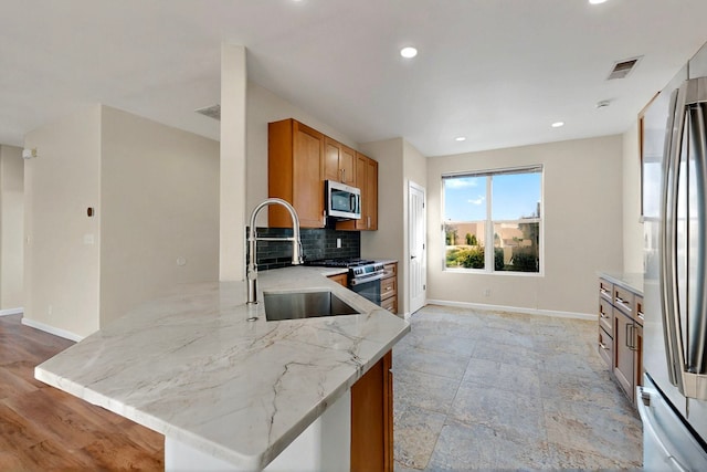 5 Wood Flower, Santa Fe, NM 87508 - kitchen with appliances with stainless steel finishes, brown cabinetry, light stone countertops, backsplash, and a peninsula