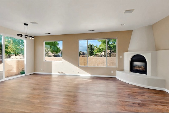 5 Wood Flower, Santa Fe, NM 87508 - unfurnished living room featuring plenty of natural light, wood finished floors, a fireplace, and a chandelier